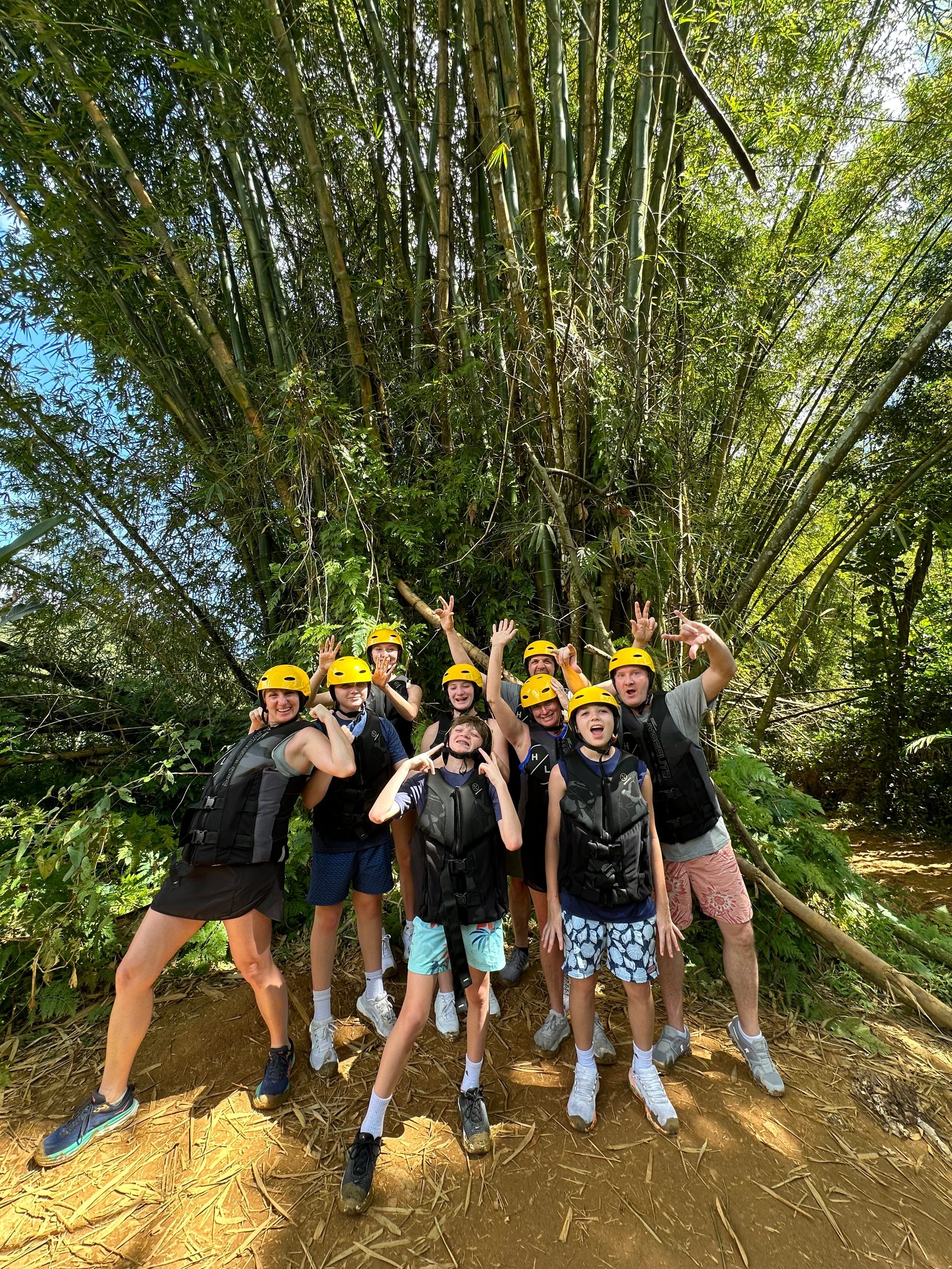 Group of people in helmets and gear posing in front of bamboo trees.