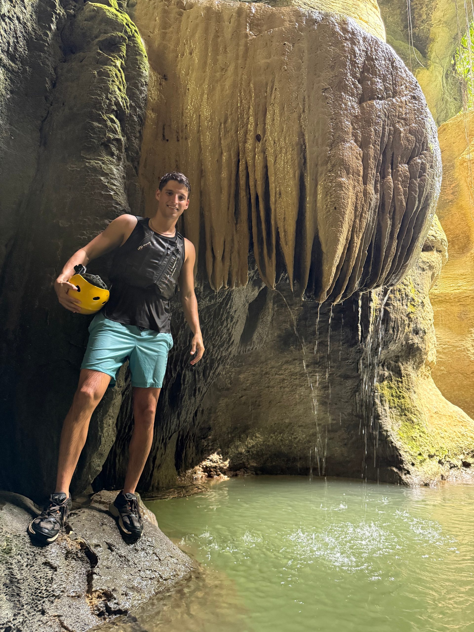 Person in athletic outfit beside a rock formation with dripping water.