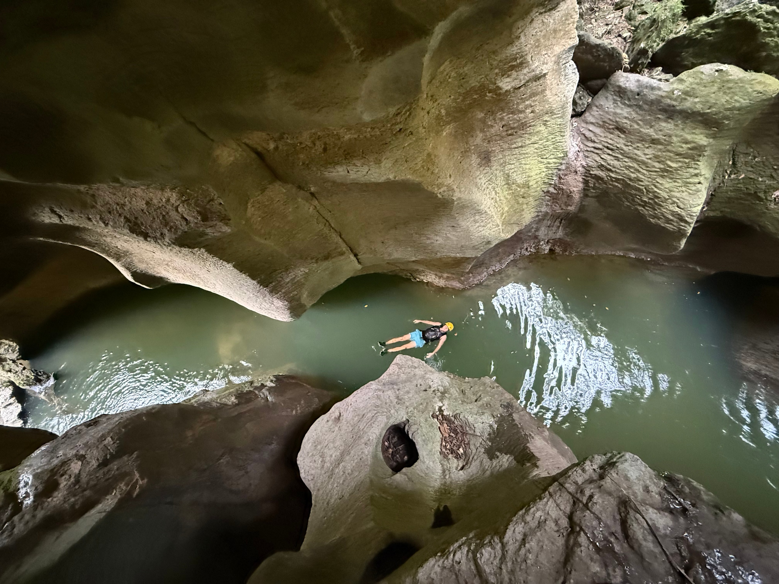 Person floating in a narrow, rocky canyon waterway.