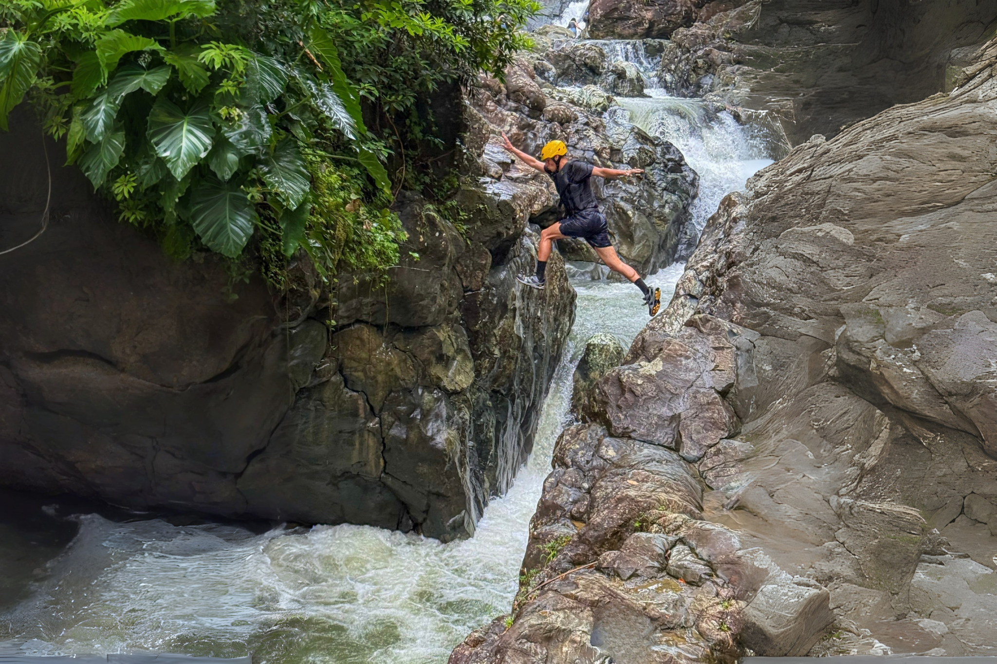 Person jumping over a rocky waterfall in a jungle setting.