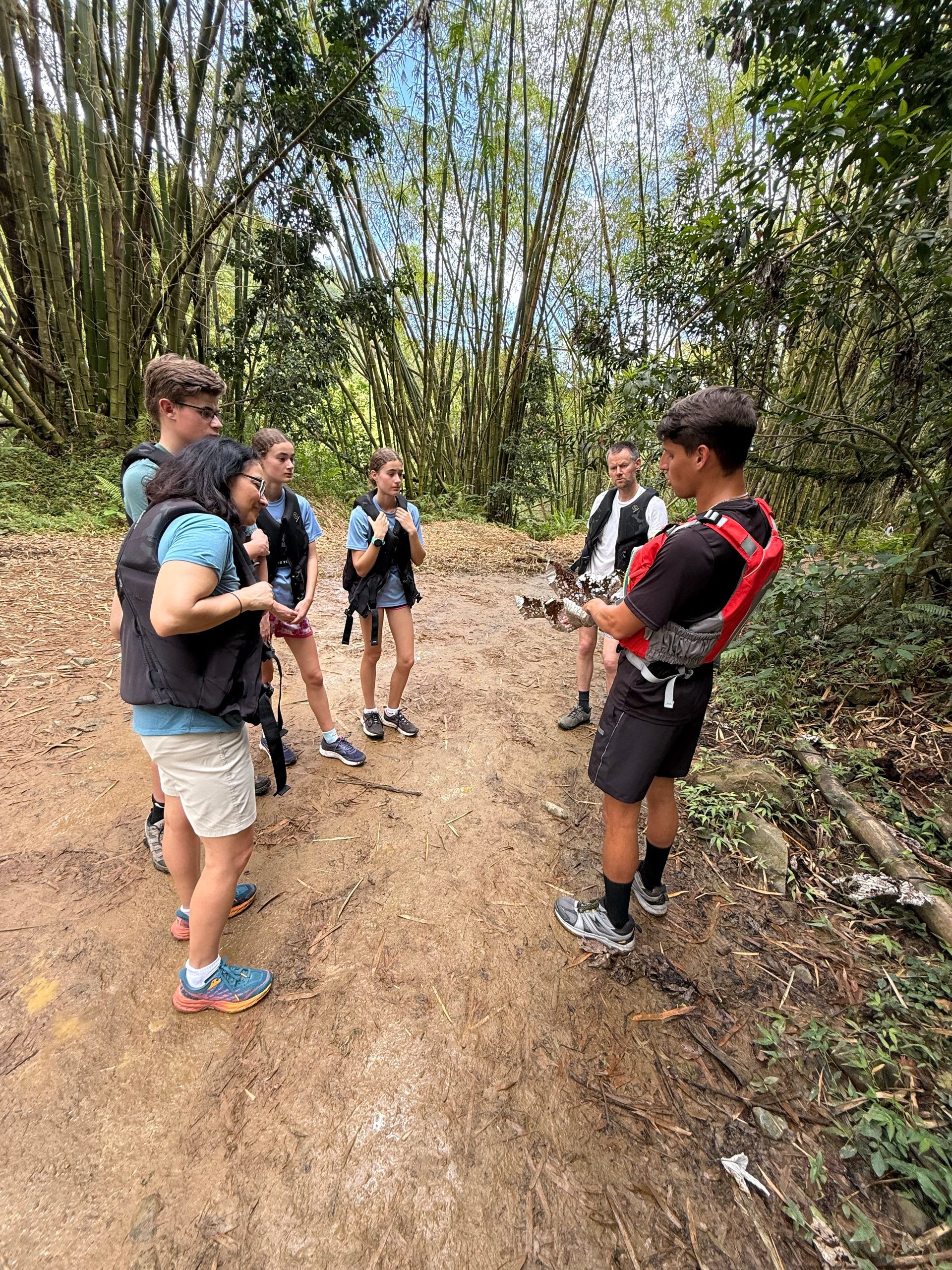 Group of hikers listening to guide in forested area.